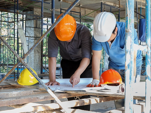 Construction management two men with hardhats looking at plans